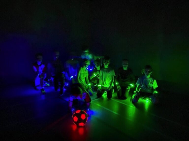 LED Voetbal Rotterdam. Kinderen in LED bandjes in een verduisterde gymzaal, klaar om te beginnen.