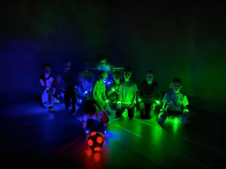 LED Voetbal Rotterdam. Kinderen in LED bandjes in een verduisterde gymzaal, klaar om te beginnen.