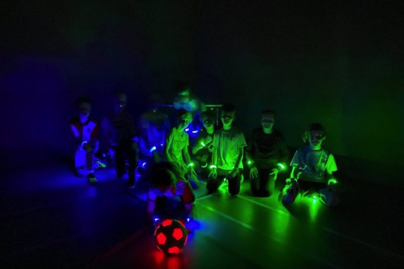 LED Voetbal LED Voetbal Rotterdam. Kinderen in LED bandjes in een verduisterde gymzaal, klaar om te beginnen.