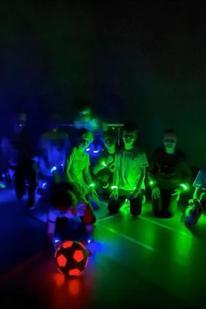 LED Voetbal Rotterdam. Kinderen in LED bandjes in een verduisterde gymzaal, klaar om te beginnen.